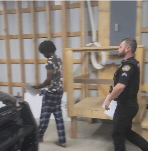 Following his arraignment Tuesday on felony charges of terroristic threats, Isaiah Randall is returned to a police cruiser by South Williamsport Cpl. Trent Dunlap. Randall was jailed in lieu of $125,000 bail. PHILIP HOLMES/Sun-Gazette